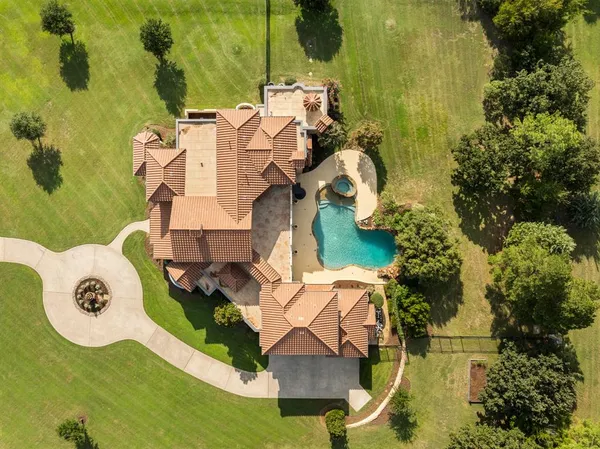 an aerial view of a house with swimming pool and large trees