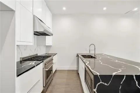 a kitchen with stainless steel appliances granite countertop a stove and a wooden floors
