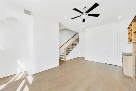 a view of an empty room with a window and wooden floor