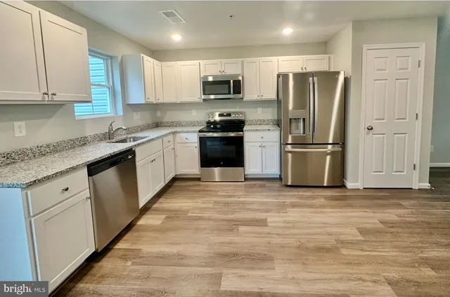 a kitchen with granite countertop a refrigerator and a stove top oven