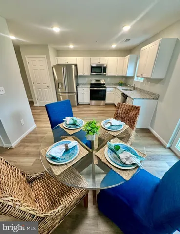 a living room with white couches and a dining table with wooden floor