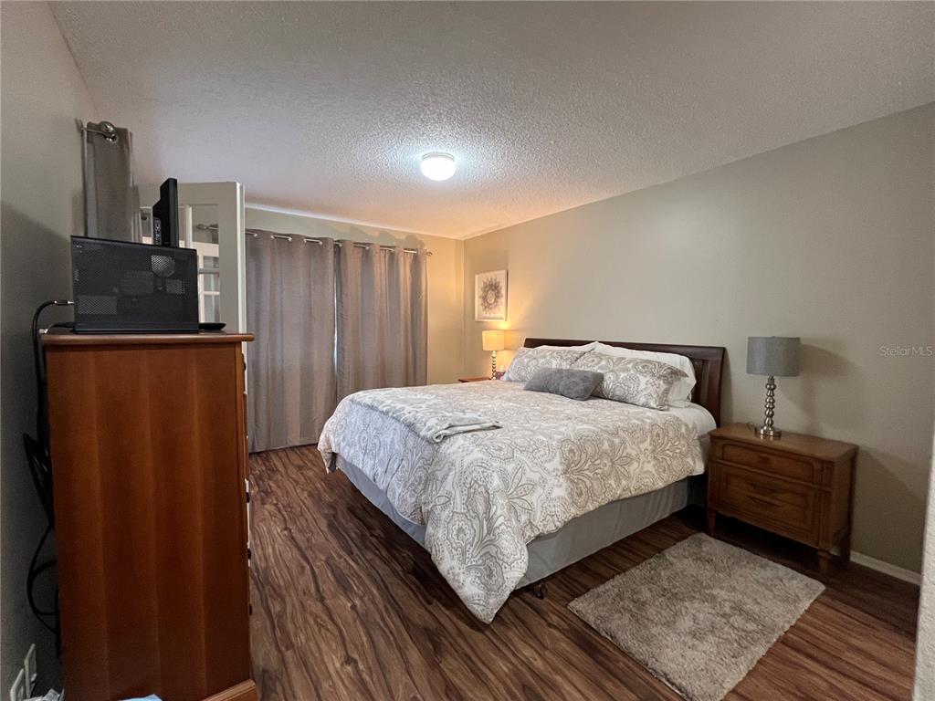 9609 Midiron Court, Unit 1 New Port Richey, FL 34655 - Photo 11 of 16 a bedroom with a bed and wooden floor