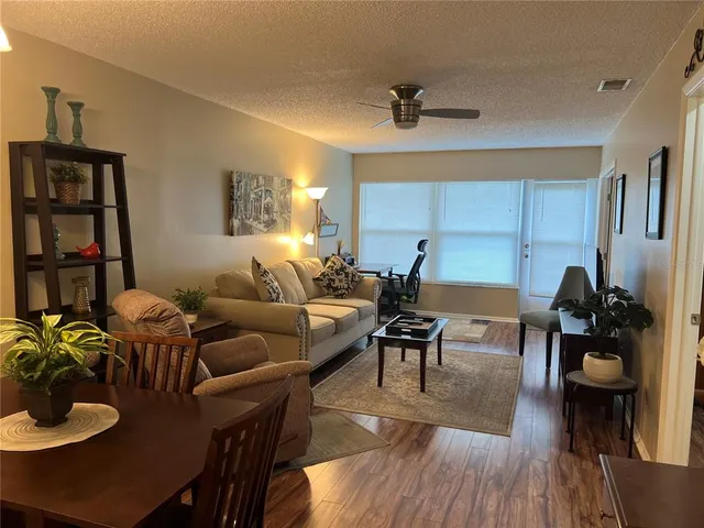 a living room with furniture kitchen view and a wooden floor