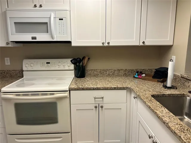 a kitchen with granite countertop white cabinets and white appliances