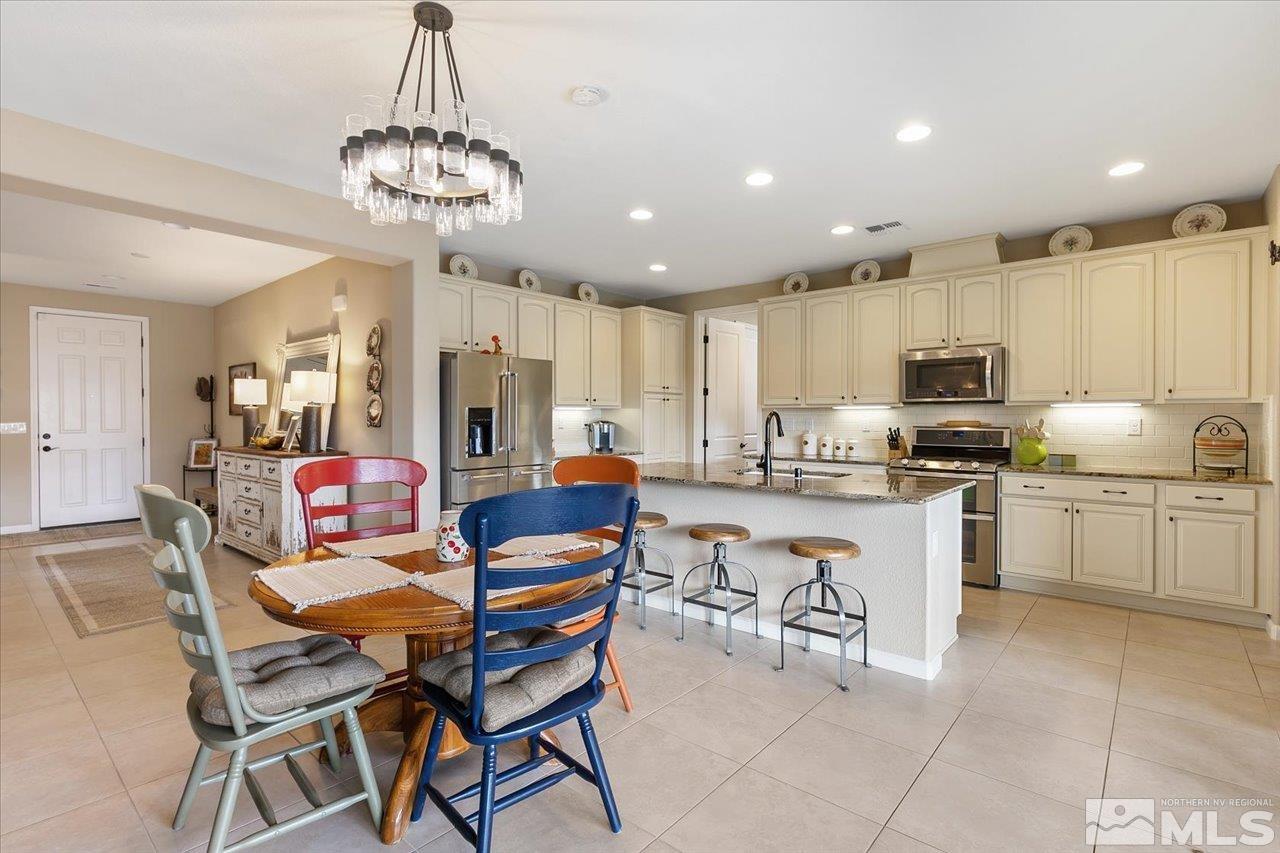 2280 Trakehner Lane Reno, NV 89521 - Photo 4 of 24 a kitchen with stainless steel appliances granite countertop a stove top oven a sink dishwasher a dining table and chairs with wooden floor