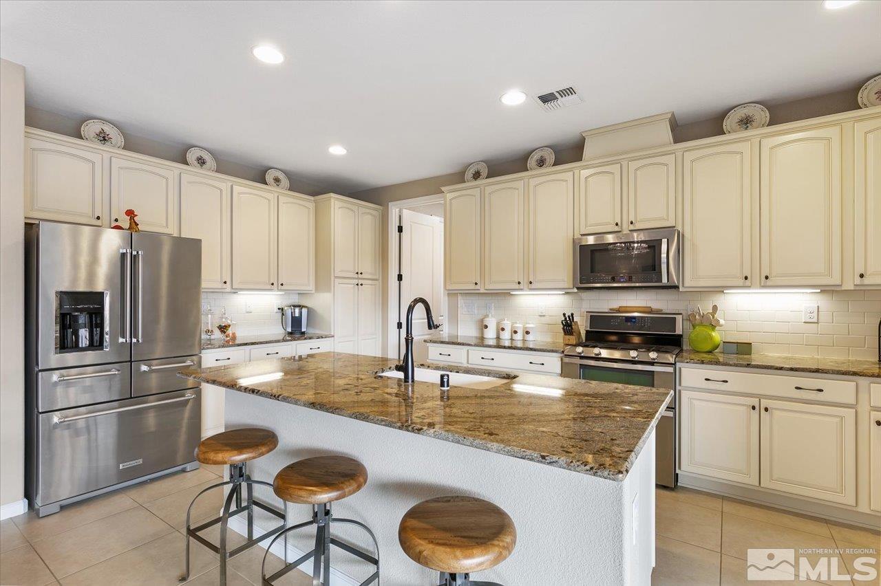 2280 Trakehner Lane Reno, NV 89521 - Photo 7 of 24 a kitchen with granite countertop a sink stainless steel appliances and white cabinets