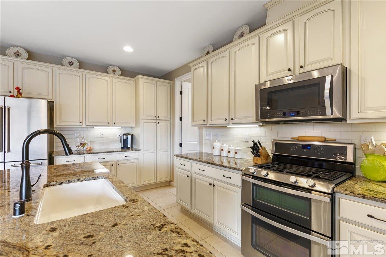 2280 Trakehner Lane Reno, NV 89521 - Photo 8 of 24 a kitchen with stainless steel appliances granite countertop a stove a sink dishwasher and a microwave with granite countertops