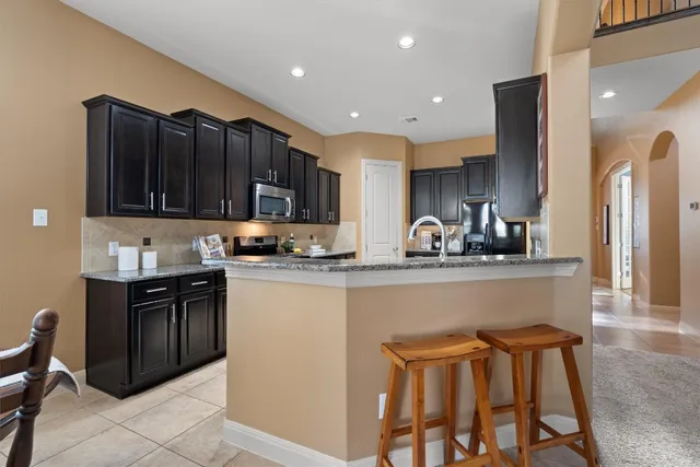a kitchen with stainless steel appliances granite countertop wooden cabinets a refrigerator and a stove top oven