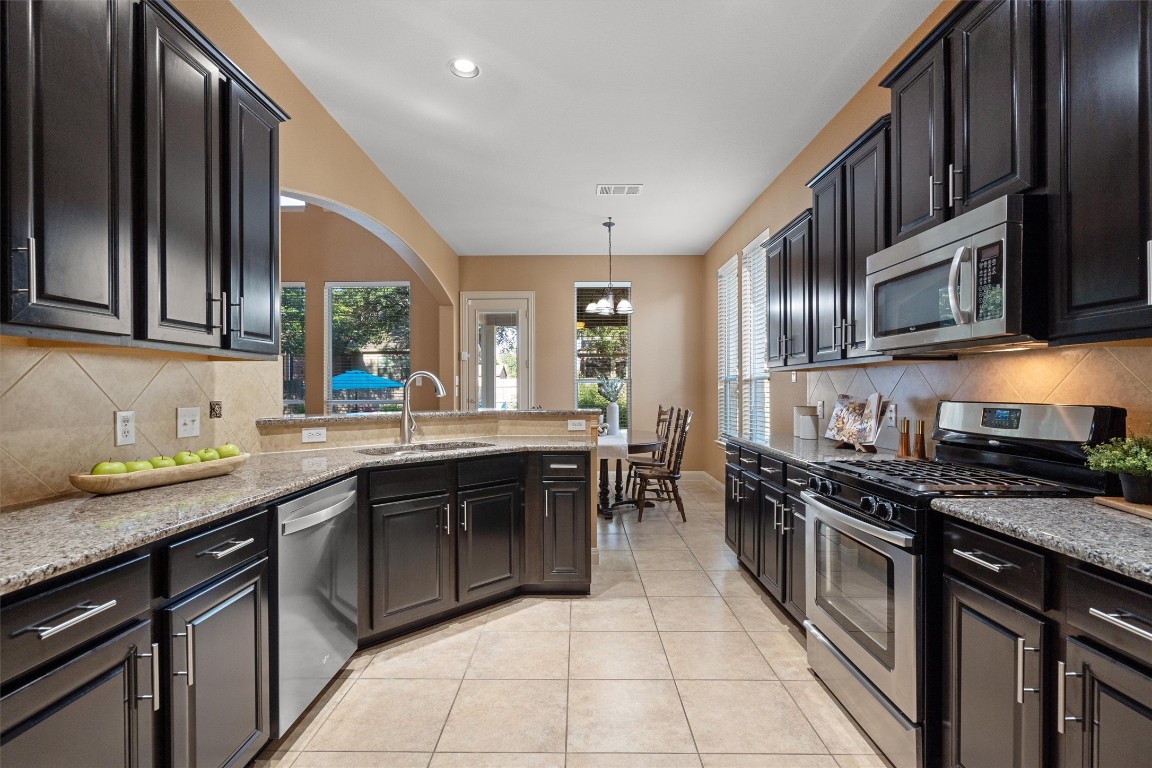1425 Naranjo Drive Georgetown, TX 78628 - Photo 16 of 38 a kitchen with stainless steel appliances granite countertop a sink stove and cabinets