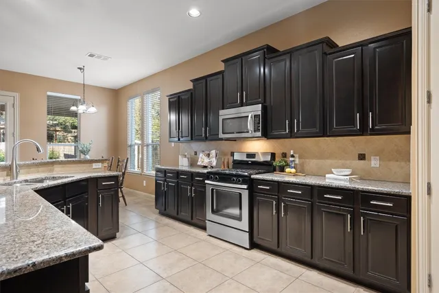 a kitchen with stainless steel appliances granite countertop a stove a sink dishwasher and a microwave oven with cabinets