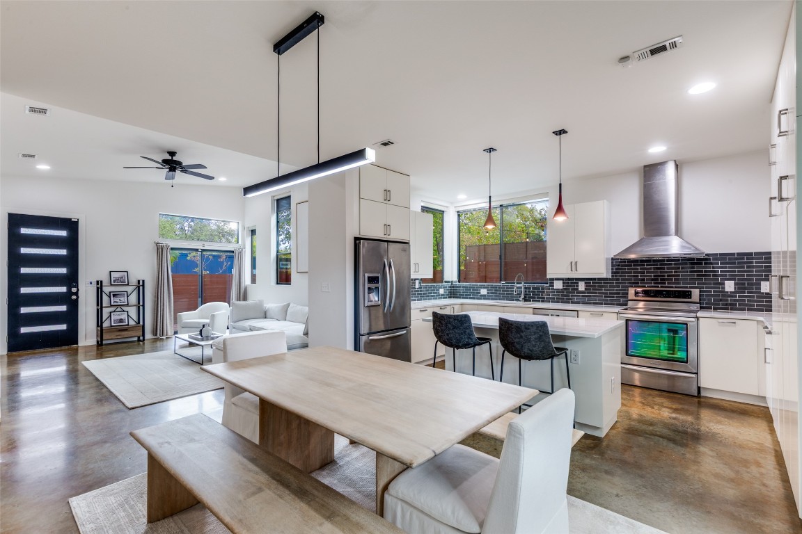a kitchen with refrigerator a stove and chairs