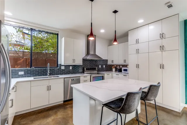 a kitchen with stainless steel appliances granite countertop a stove a refrigerator a sink a dining table and chairs with wooden floor