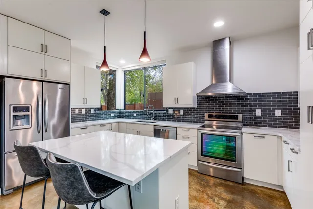 a kitchen with stainless steel appliances granite countertop a stove a sink a microwave a refrigerator and chairs