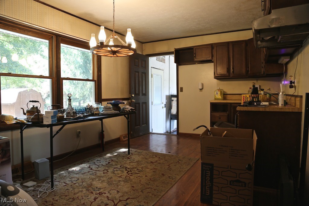 10054 Smith Road Litchfield, OH 44253 - Photo 3 of 9 Kitchen with pendant lighting, dark brown cabinets, dark hardwood / wood-style floors, extractor fan, and a notable chandelier