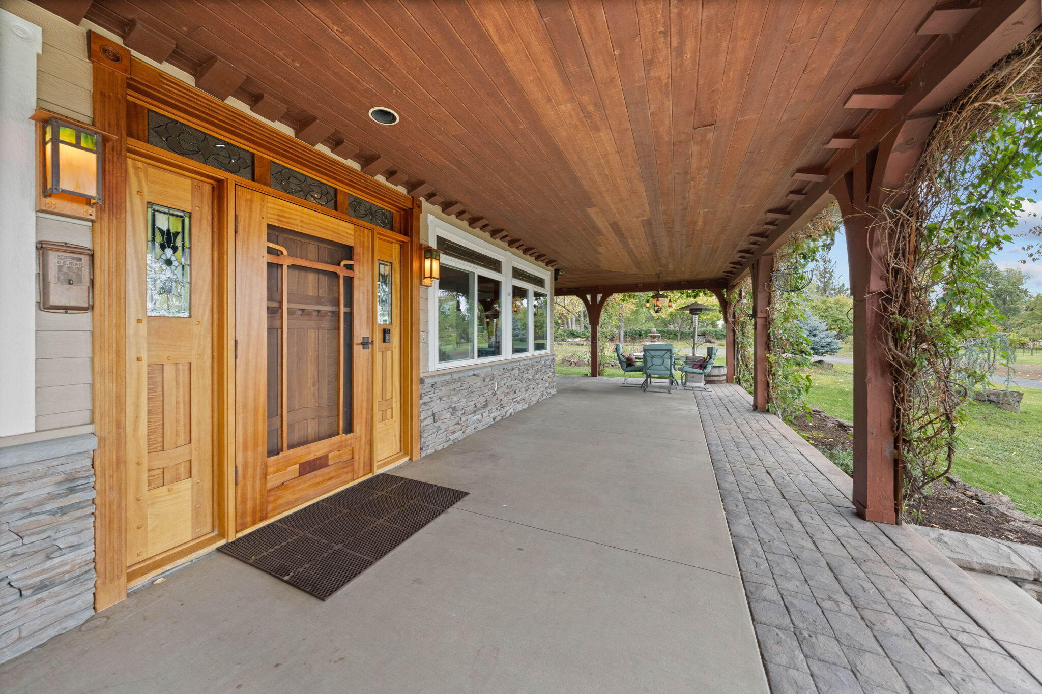 21925 Bear Creek Road Bend, OR 97702 - Photo 15 of 104 Front entryway door is Brazilian cherry w/African mahogany screen doors in the Green & Green style. Large concrete covered porch with wisteria, Virginia creeper and silver lace vines.