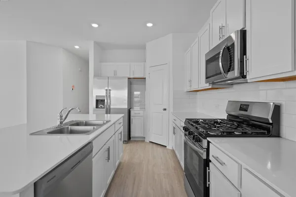a kitchen with stainless steel appliances granite countertop a refrigerator a sink a stove a microwave and white cabinets
