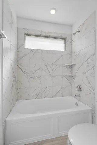 a bathroom with a toilet a sink a mirror a bathtub and vanity