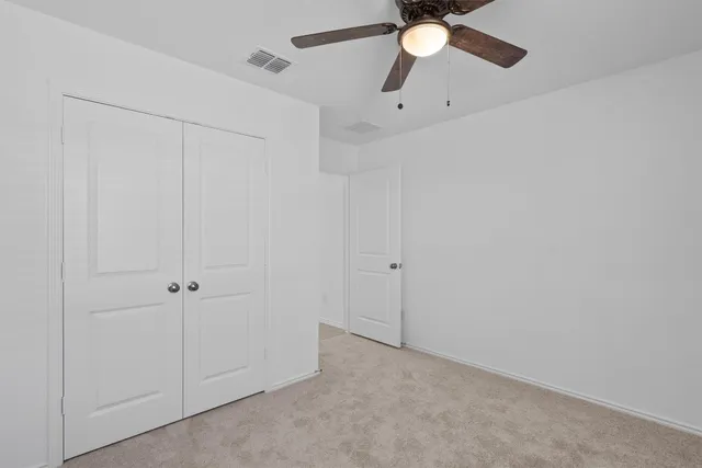 an empty room with ceiling fan and window