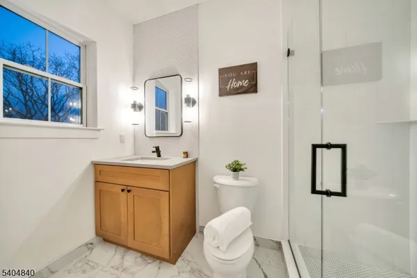 a bathroom with a toilet a sink a mirror a window and vanity