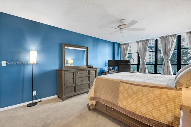 a bedroom with a bed dresser and a large window