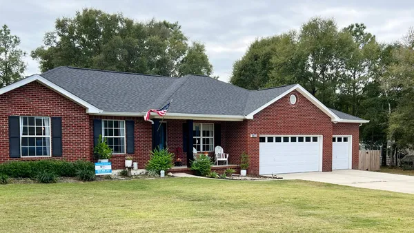 a front view of a house with a yard garden and outdoor seating