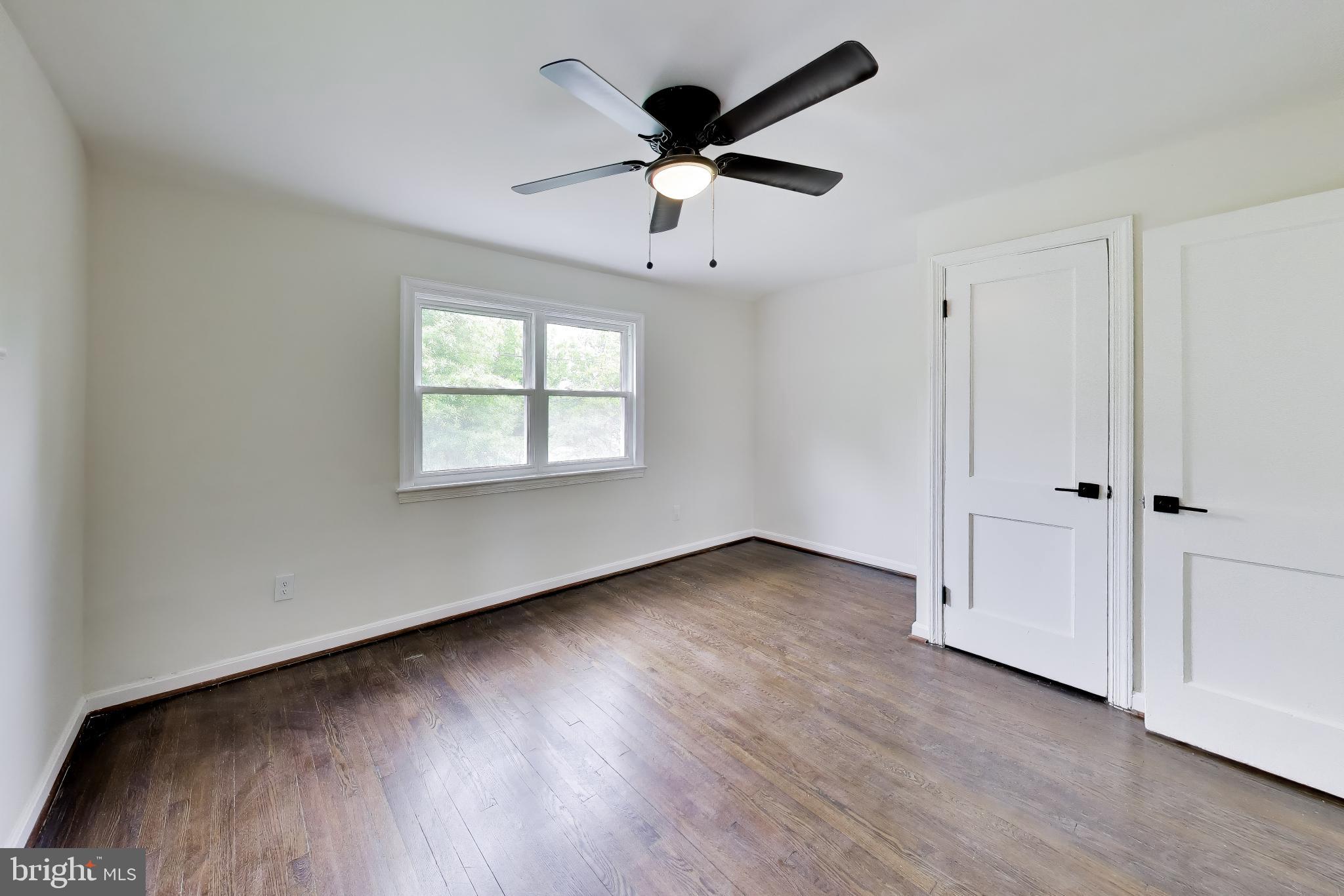 186 Forrester Street Southwest Washington, DC 20032 - Photo 13 of 32 an empty room with wooden floor ceiling fan and windows