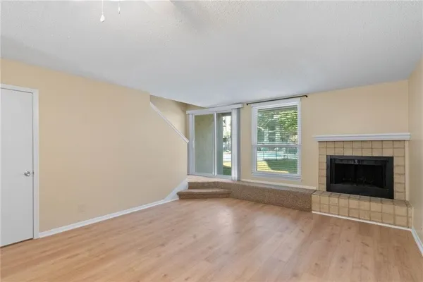 an empty room with wooden floor fireplace and windows
