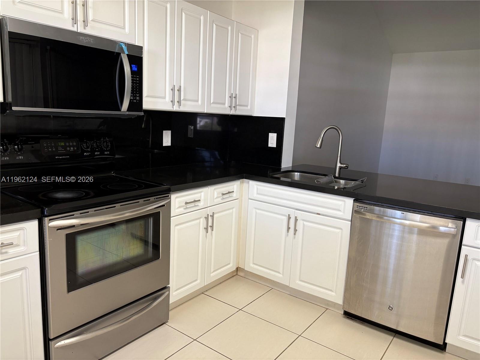 Boca del Mar Boca Raton, FL 33433 - Photo 33 of 41 a kitchen with white cabinets and black appliances
