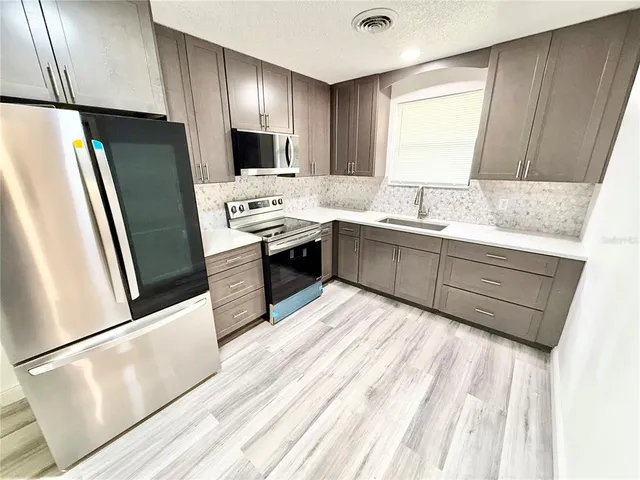a kitchen with stainless steel appliances a refrigerator sink and wooden floor
