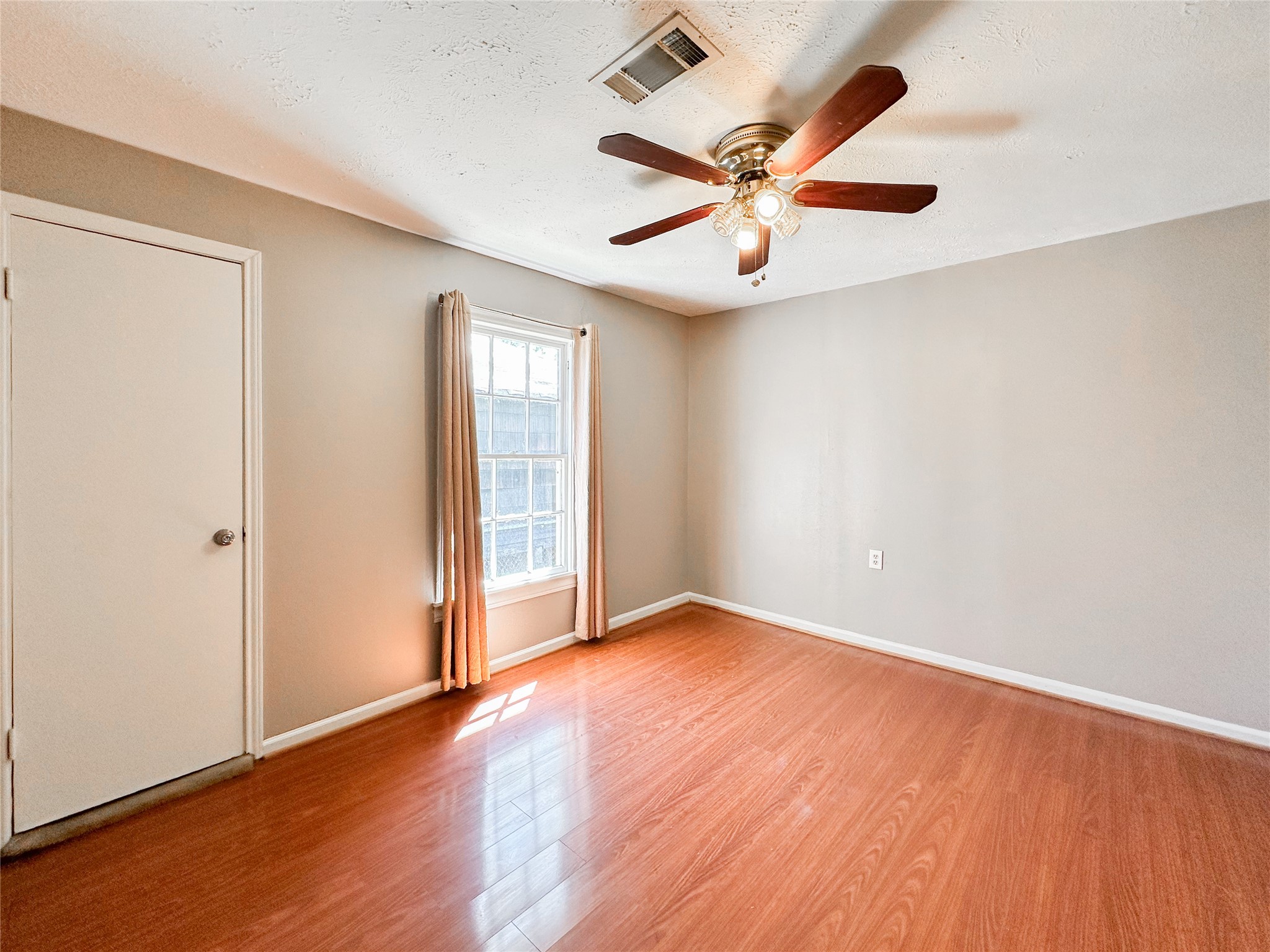 132 Grothe Lane Houston, TX 77022 - Photo 14 of 36 an empty room with wooden floor fan and windows