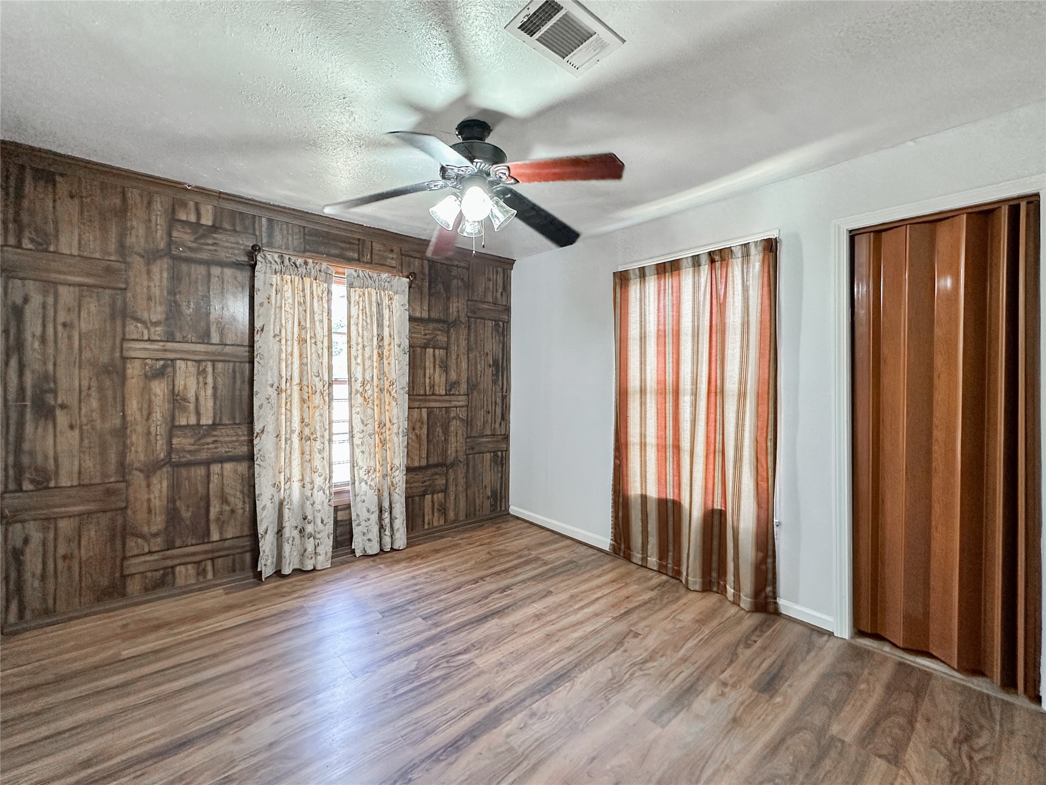 132 Grothe Lane Houston, TX 77022 - Photo 9 of 36 an empty room with wooden floor fan and windows