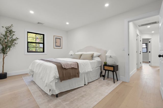 a spacious bedroom with a bed and a painting on the wall