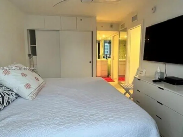 a bedroom with a bed and a flat tv screen on dresser