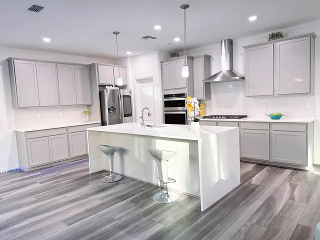 a large kitchen with stainless steel appliances granite countertop a stove a sink dishwasher and a refrigerator with wooden floor