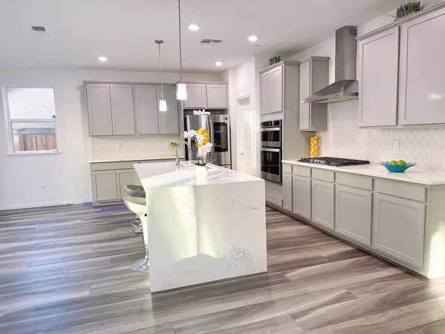 a kitchen with stainless steel appliances granite countertop a sink a stove and a wooden floors