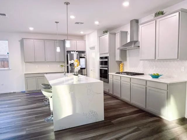 a kitchen with stainless steel appliances granite countertop a stove a sink dishwasher and a refrigerator with white cabinets