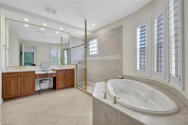 a large spacious bathroom with a tub a double vanity sink a window and a mirror