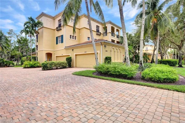 a front view of a multi story residential apartment building with yard and parking