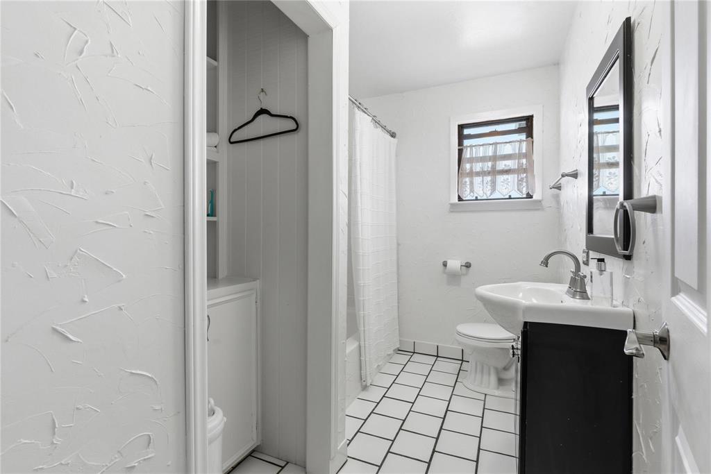 9213 Wilson Road Pilot Point, TX 76258 - Photo 23 of 36 Bathroom with a square tiled floor, a dark wood-finish vanity, a pedestal sink, a window with a dark frame, and a built-in storage cabinet