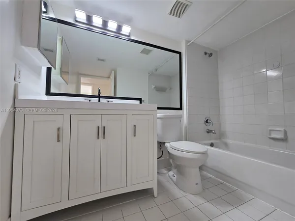 a bathroom with a granite countertop sink a toilet a mirror and bathtub