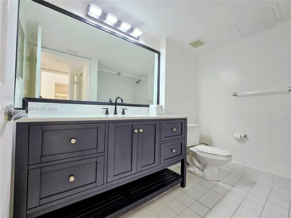 a bathroom with a toilet a double vanity sink and a mirror