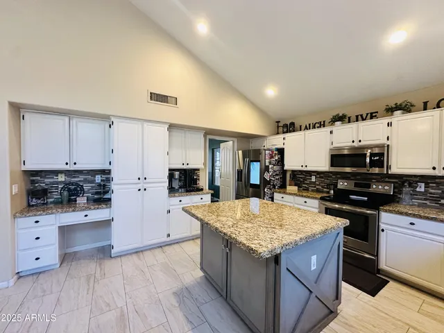 a kitchen with stainless steel appliances granite countertop a stove top oven a sink dishwasher and a refrigerator with wooden floor