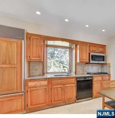 a kitchen with stainless steel appliances granite countertop a refrigerator a sink a stove a microwave and cabinets