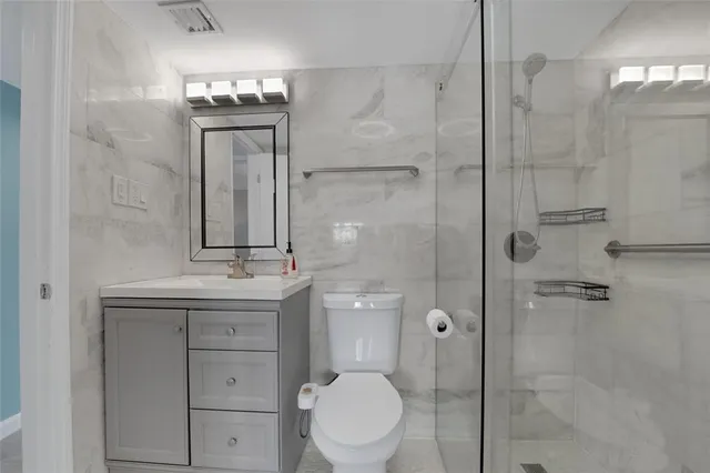 a bathroom with a toilet a sink shower and mirror