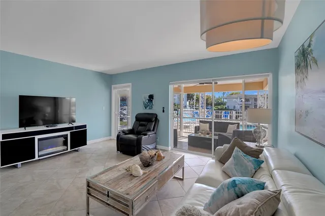 a living room with furniture a flat screen tv and floor to ceiling window