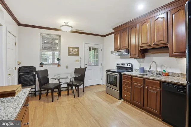 a open kitchen with stainless steel appliances granite countertop a stove top oven a sink dishwasher and cabinets with wooden floor