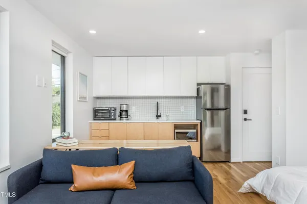 a living room with stainless steel appliances kitchen island granite countertop a refrigerator and a couch