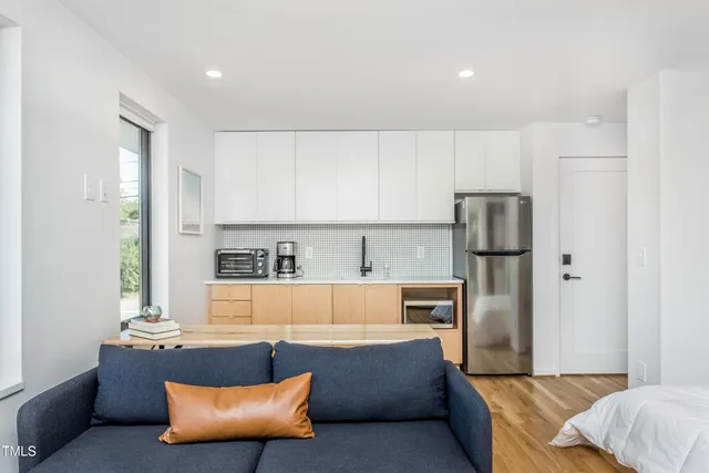 a living room with stainless steel appliances kitchen island granite countertop a refrigerator and a couch
