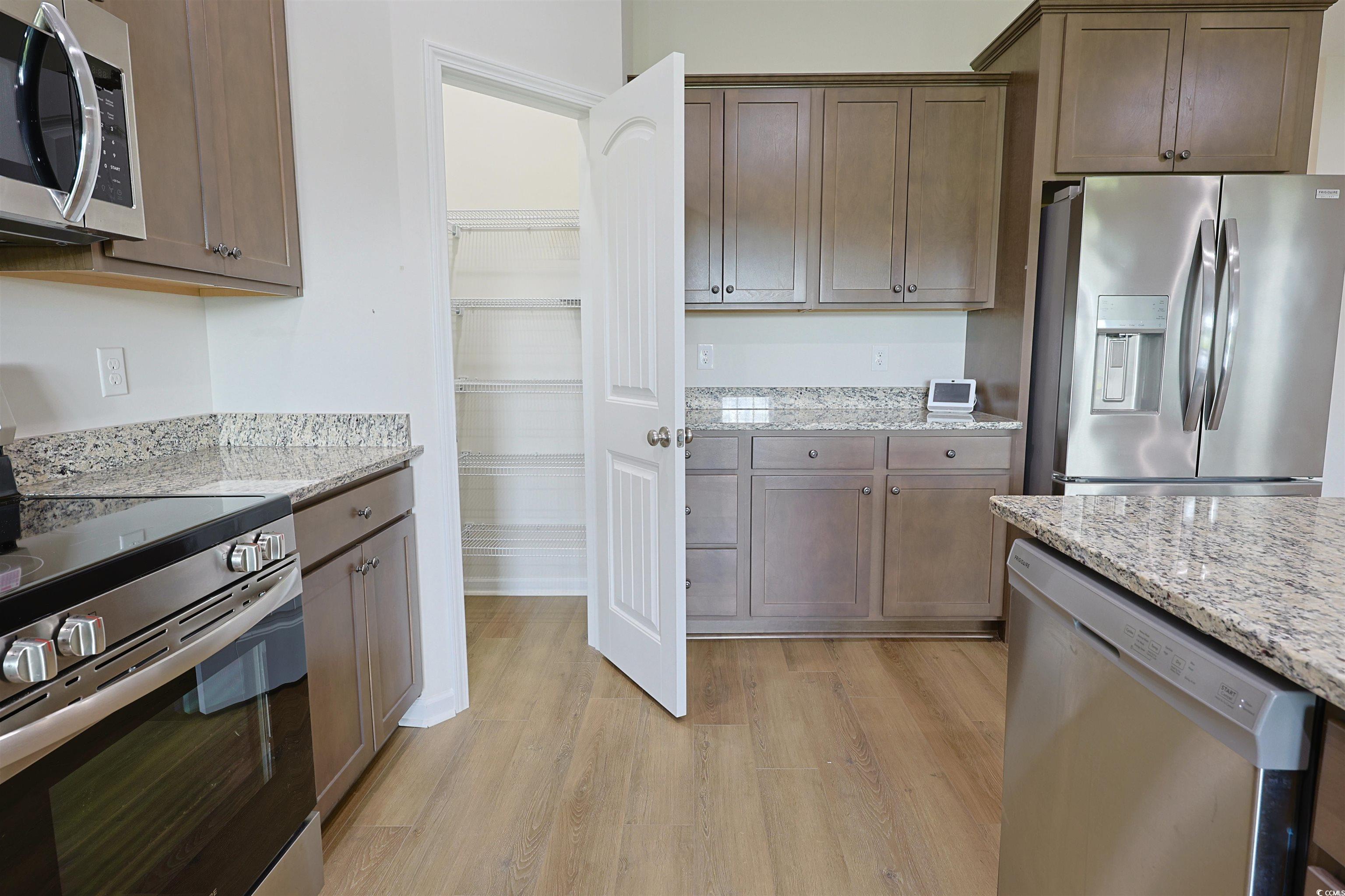 266 Ole Maple Street Loris, SC 29569 - Photo 7 of 30 Kitchen with stainless steel appliances, light wood-style flooring, light stone countertops, and dark brown cabinetry