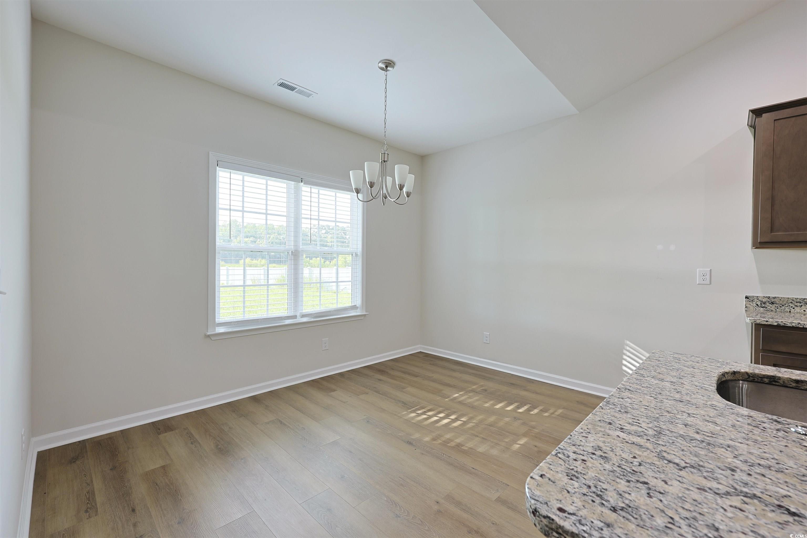 266 Ole Maple Street Loris, SC 29569 - Photo 9 of 30 Unfurnished dining area with wood finished floors and a chandelier